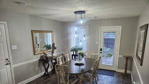 A dining room with a dark wood table and chairs, a large mirror, and a door leading to an outdoor area. - 3bd/2bth Home, king/queen bds,crib, RV/trailer parking, pet fence, massage chair (Cabot)