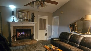A living room with a fireplace, leather sofa, and a coffee table. - 3bd/2bth Home, king/queen bds,crib, RV/trailer parking, pet fence, massage chair (Cabot)
