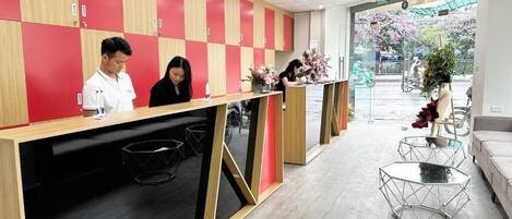 A reception area with a check-in counter, wooden lockers, and a view of the street outside.