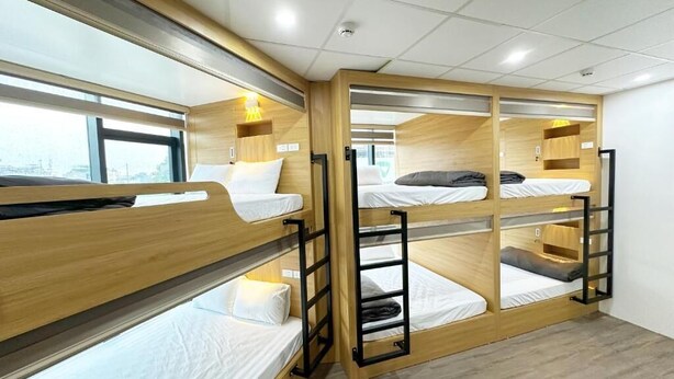 A room with bunk beds, wooden headboards, and a window providing a view. - HANOI CAPSULE STATION  (Hanoi)