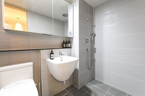 A bathroom with a white sink, a mirror, a shower, and a toilet. - Marant Residence Hotel (Busan)