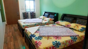 Una habitación con dos camas, una ventana con barrotes, una puerta y una pared verde.