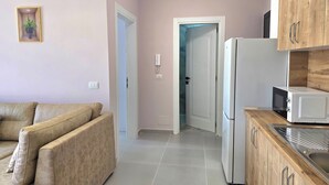 A modern kitchen with a refrigerator, microwave, and wooden cabinets. - Happy Stay Apartment By The Sea 094 (Golem)