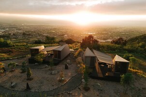 Um hotel moderno em estilo de cabana, isolado, com várias unidades, cercado por paisagem natural e vista para uma cidade distante.