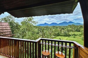 A wooden balcony with a view of a lush landscape and mountains. - Four Mountains Villa Bedugul  (Mekarsari)