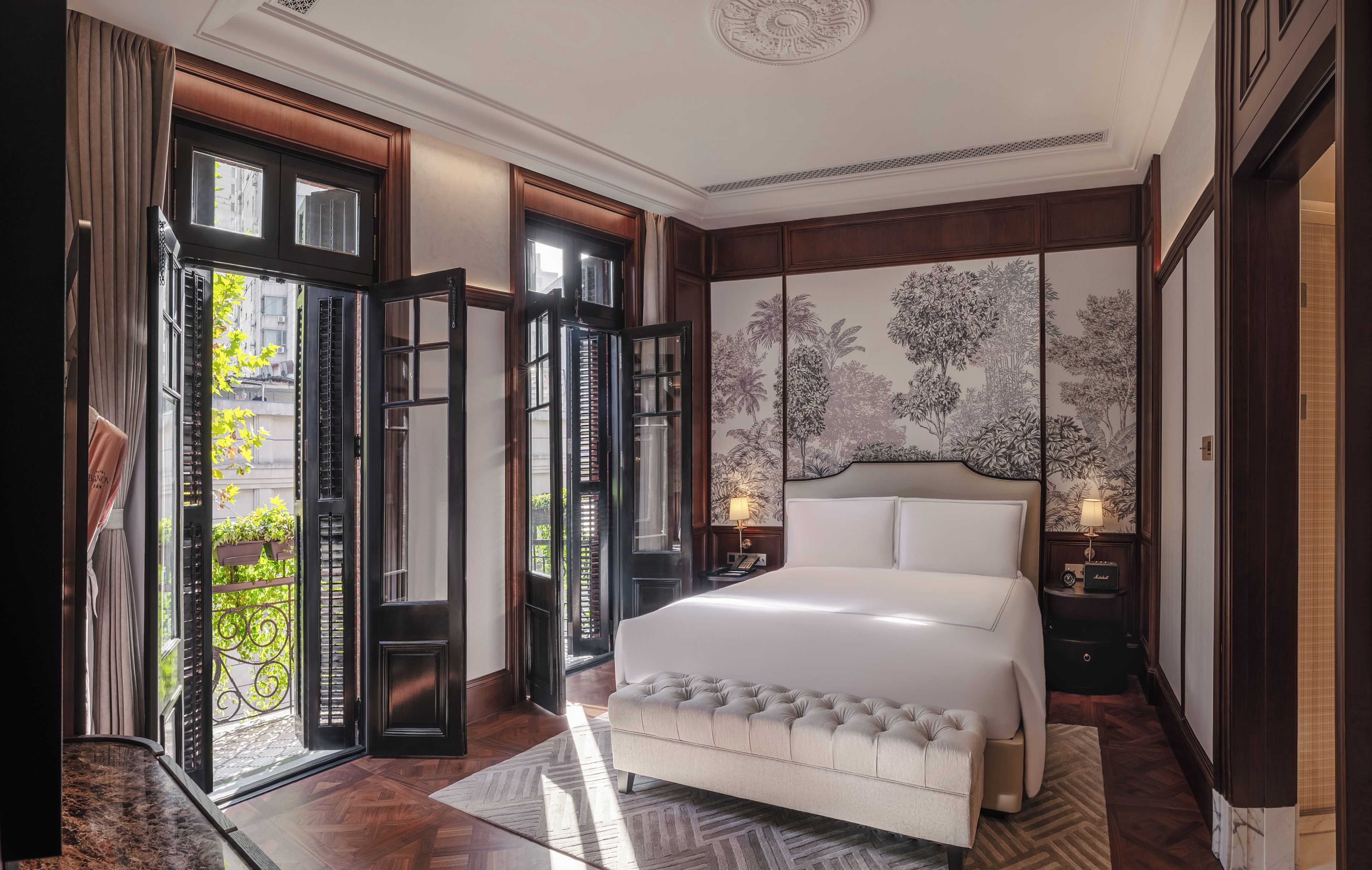 A spacious bedroom with a large bed, a view of the outdoors through open doors, and a decorative wall mural.