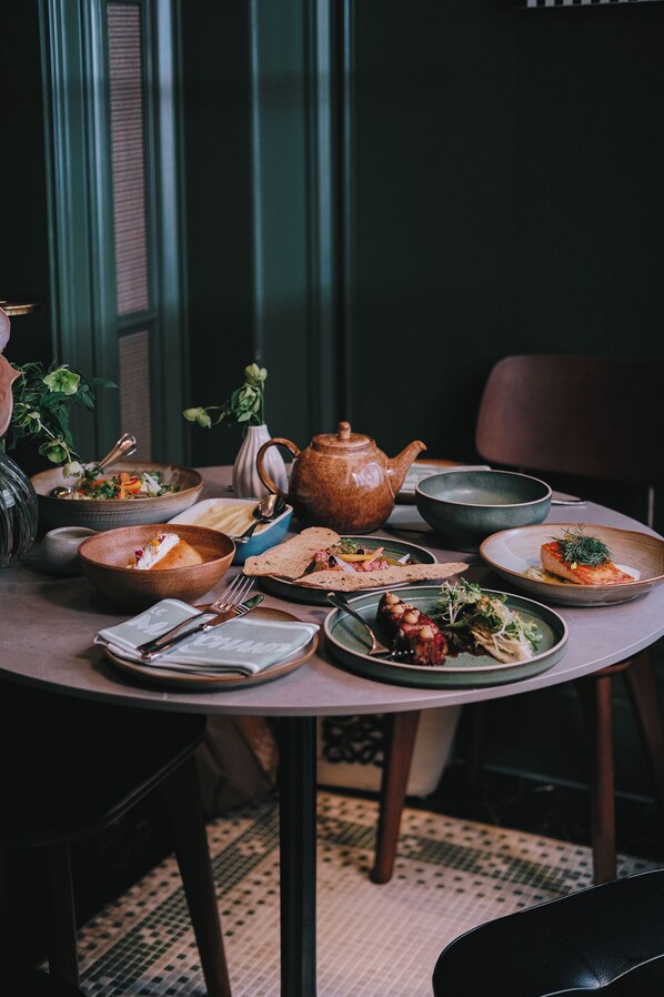 A dining table set with various dishes, a teapot, and a vase with flowers. - Hotel Banov Townscape Wuhan (Wuhan)