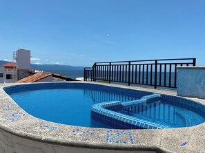 Une piscine sur le toit offrant une vue dégagée sur la mer et les montagnes en arrière-plan.