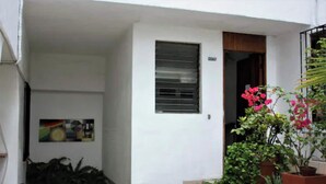 A white building with a small entrance, a metal window, and potted plants outside. - Ocean view apartment in downtown Vallarta a few steps from the Malecon (Puerto Vallarta)