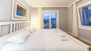 Un dormitorio con una cama grande, una mesita de noche, una lámpara y vistas al exterior a través de una puerta corrediza.