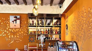 A bar area with wooden stools, a counter with a cash register, and shelves stocked with bottles. - Paro Eco-Nest Resort (Paro)