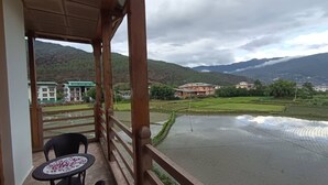 A balcony with a view of terraced rice fields and mountains. - Paro Eco-Nest Resort (Paro)