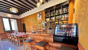 A restaurant with wooden tables and chairs, a bar area with shelves of bottles, and a decorative wall with floral patterns. - Paro Eco-Nest Resort (Paro)