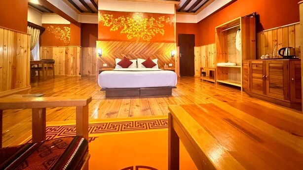A wooden-floored room with a bed, a table, and a cabinet. - Paro Eco-Nest Resort (Paro)
