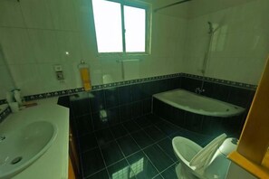 A bathroom with a sink, toilet, bathtub, and a window. - Li Yuan Ju Hotel (Islamabad)