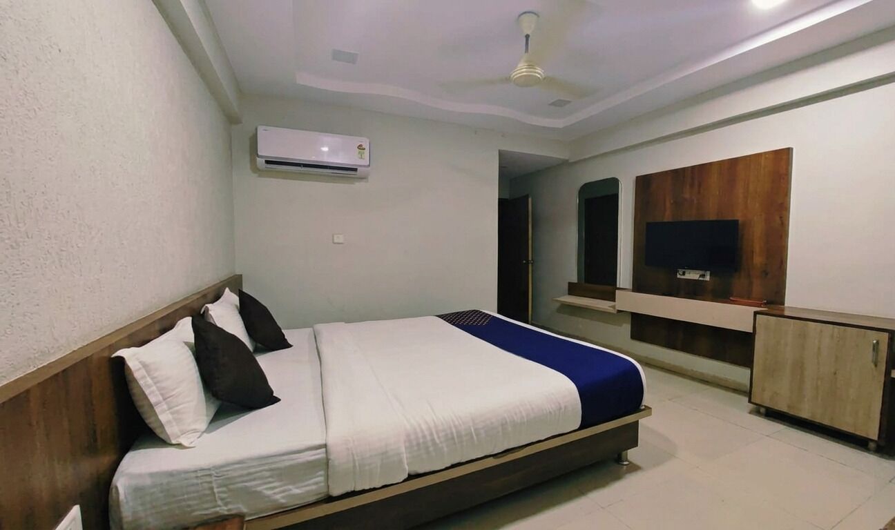 Un dormitorio con cama, ventilador de techo, aire acondicionado, televisor y armario.