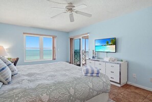 Ein Schlafzimmer mit Bett, Kommode, Fernseher und Meerblick.