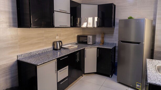 Una cocina moderna con muebles negros y blancos, electrodomésticos de acero inoxidable y encimera de granito.