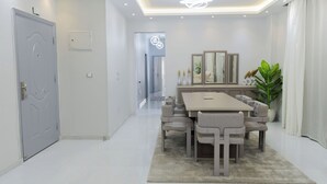Un comedor moderno con una mesa rectangular y seis sillas, una araña y una planta en maceta.