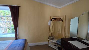 A bedroom with a bed, a dresser, a mirror, and a window with curtains.