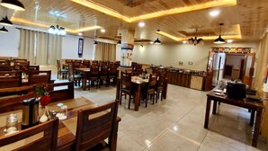A spacious restaurant with wooden furniture, multiple dining tables, ceiling fans, and pendant lighting.