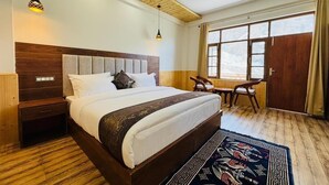 A bedroom with a large bed, wooden headboard, bedside tables, a ceiling fan, and a window with curtains.