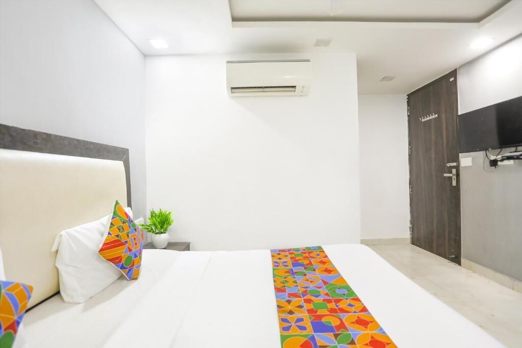A hotel room with a bed, a small potted plant, and a door.