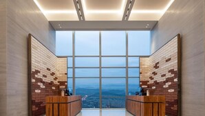 A modern lobby with a large glass wall, wooden reception desks, and a city view. - Hampton by Hilton Hangzhou Liangzhu (Hangzhou)