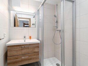Un baño moderno con ducha, un lavabo con espejo y muebles de madera.