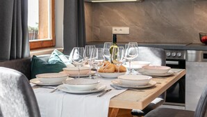 A dining table set with plates, bowls, and wine glasses, with a bottle of wine and bread on the table. - Two holiday apartments in farmhouse with a view (Alpbach)