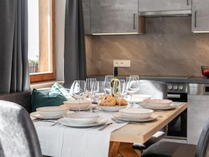 A dining table set with plates, bowls, and wine glasses, with a bottle of wine and bread on the table. - Two holiday apartments in farmhouse with a view (Alpbach)