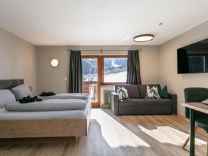 A modern bedroom with a bed, a sofa, and a TV. - Two holiday apartments in farmhouse with a view (Alpbach)