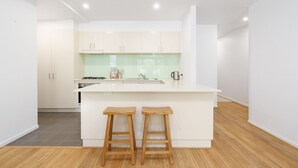 Una cocina moderna con armarios blancos, una isla central con taburetes y un salpicadero verde.