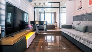 A modern living room with a flat-screen TV, a sofa, a desk with a computer, and a small table. - Air residence Makati Air Luxury Package (Makati)