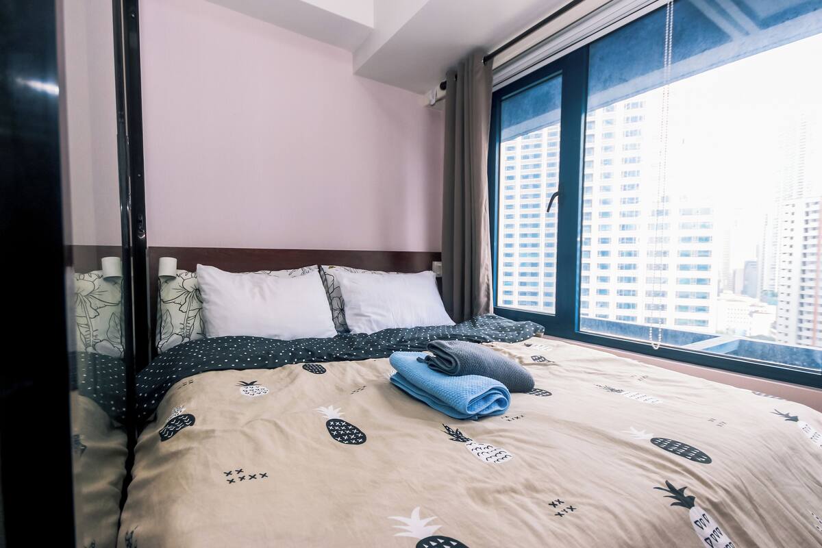 Une chambre d’hôtel avec un lit, une fenêtre donnant sur la ville et un store.