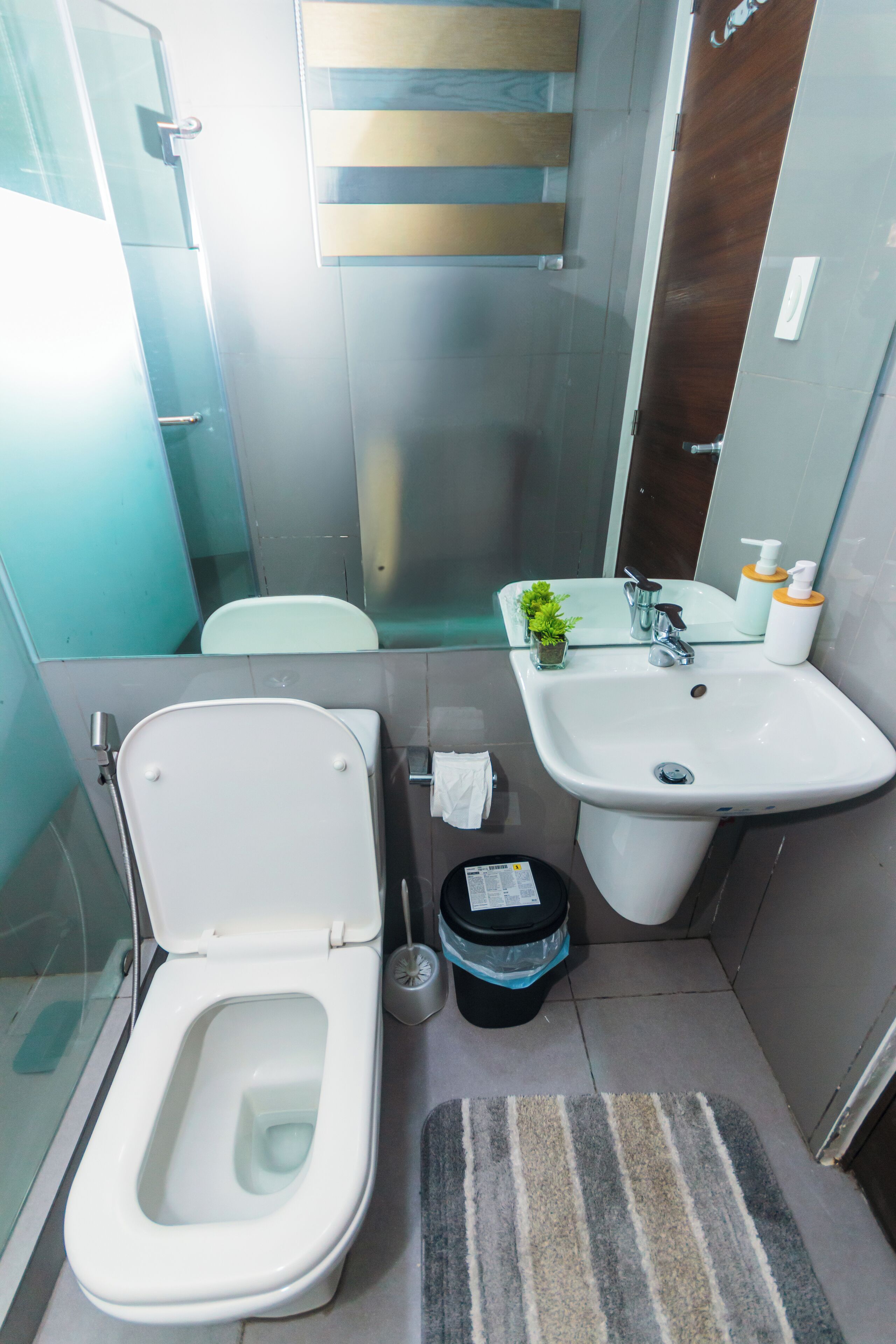 A small bathroom with a toilet, sink, and mirror.
