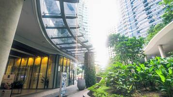 A modern building with a glass facade, a curved entrance, and a well-maintained garden area.
