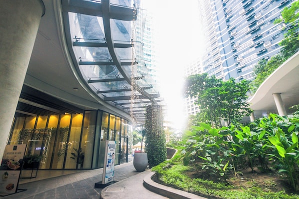A modern building with a glass facade, a curved entrance, and a well-maintained garden area.