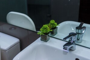 A bathroom with a white sink, a mirror, and two small potted plants. - Air residence Makati Air Luxury Package (Makati)