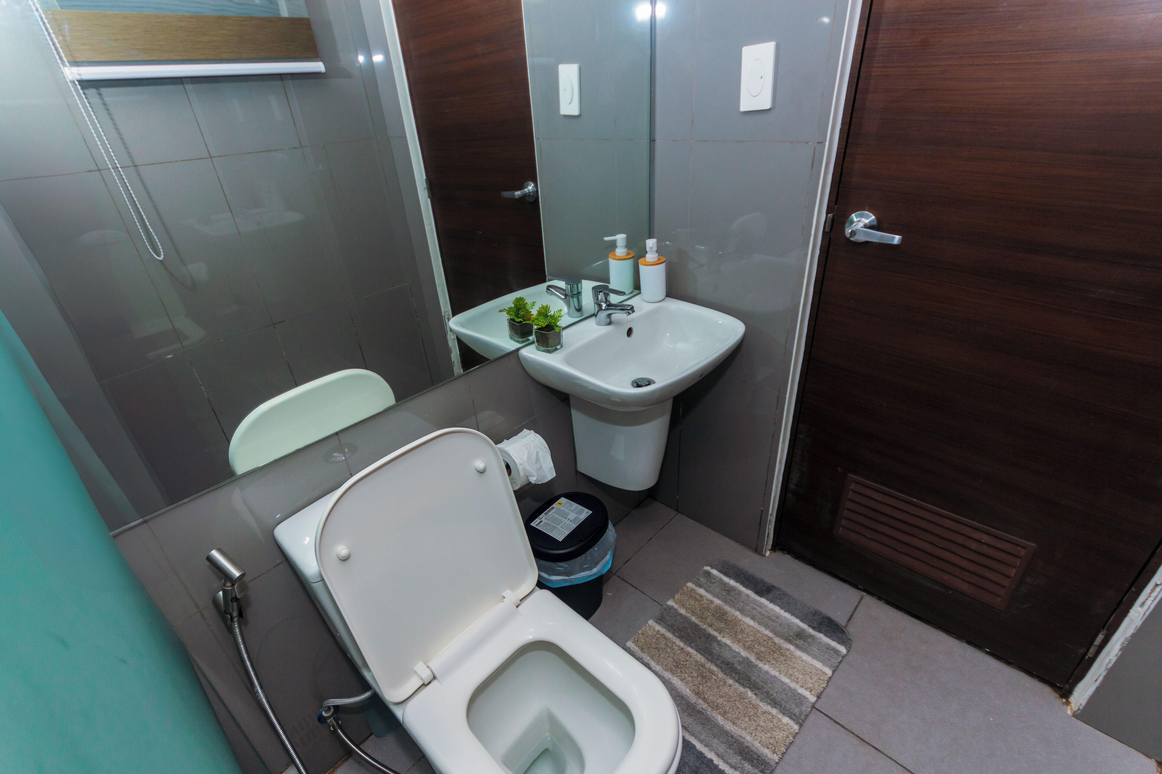 A small bathroom with a toilet, sink, and a mirror.