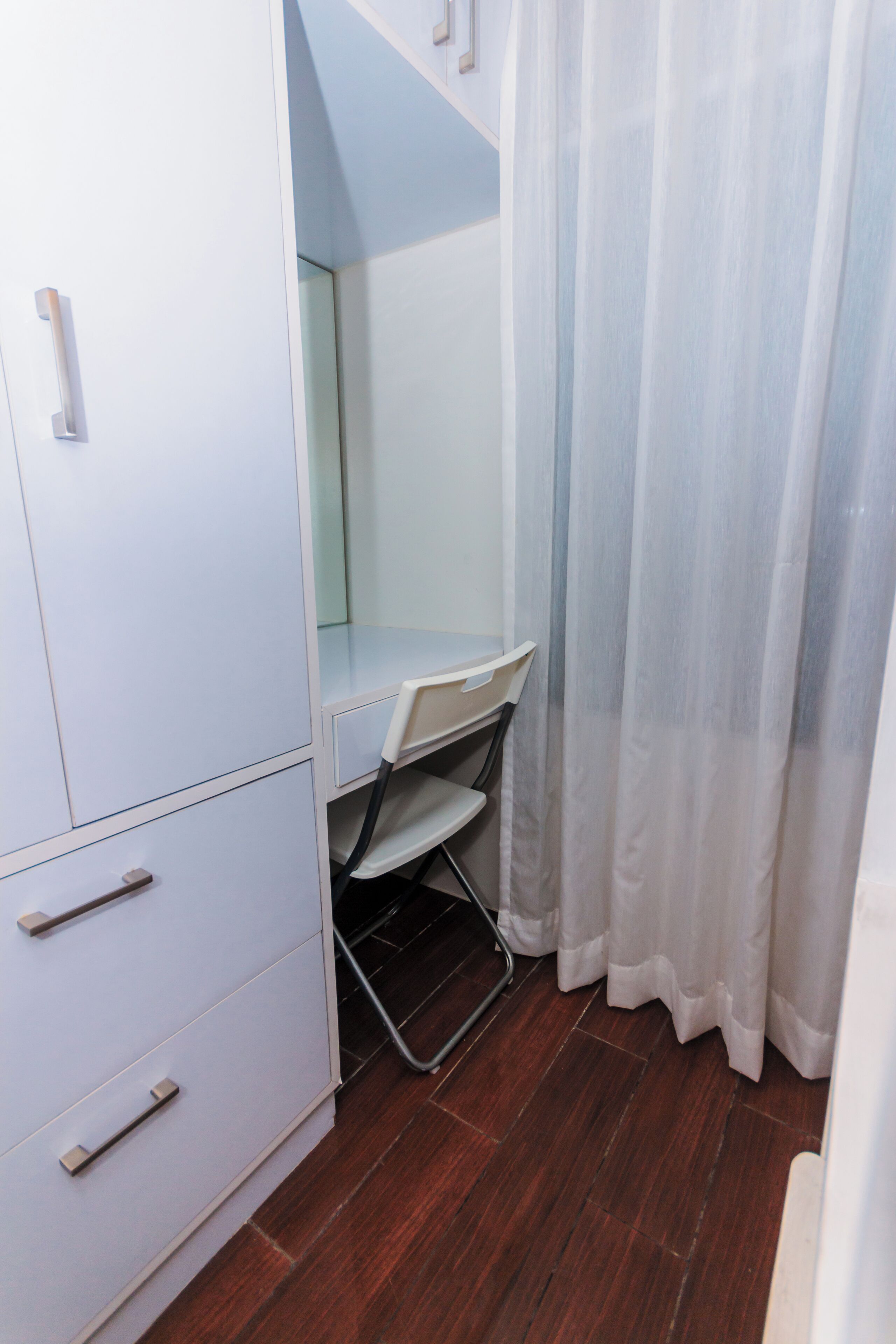 A small, private bathroom with a white cabinet, a mirror, a shower area, and a shower curtain.