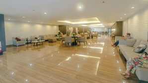 A spacious hotel lobby with a polished floor, seating areas, and a Christmas tree. - Air residence Makati Air Luxury Package (Makati)