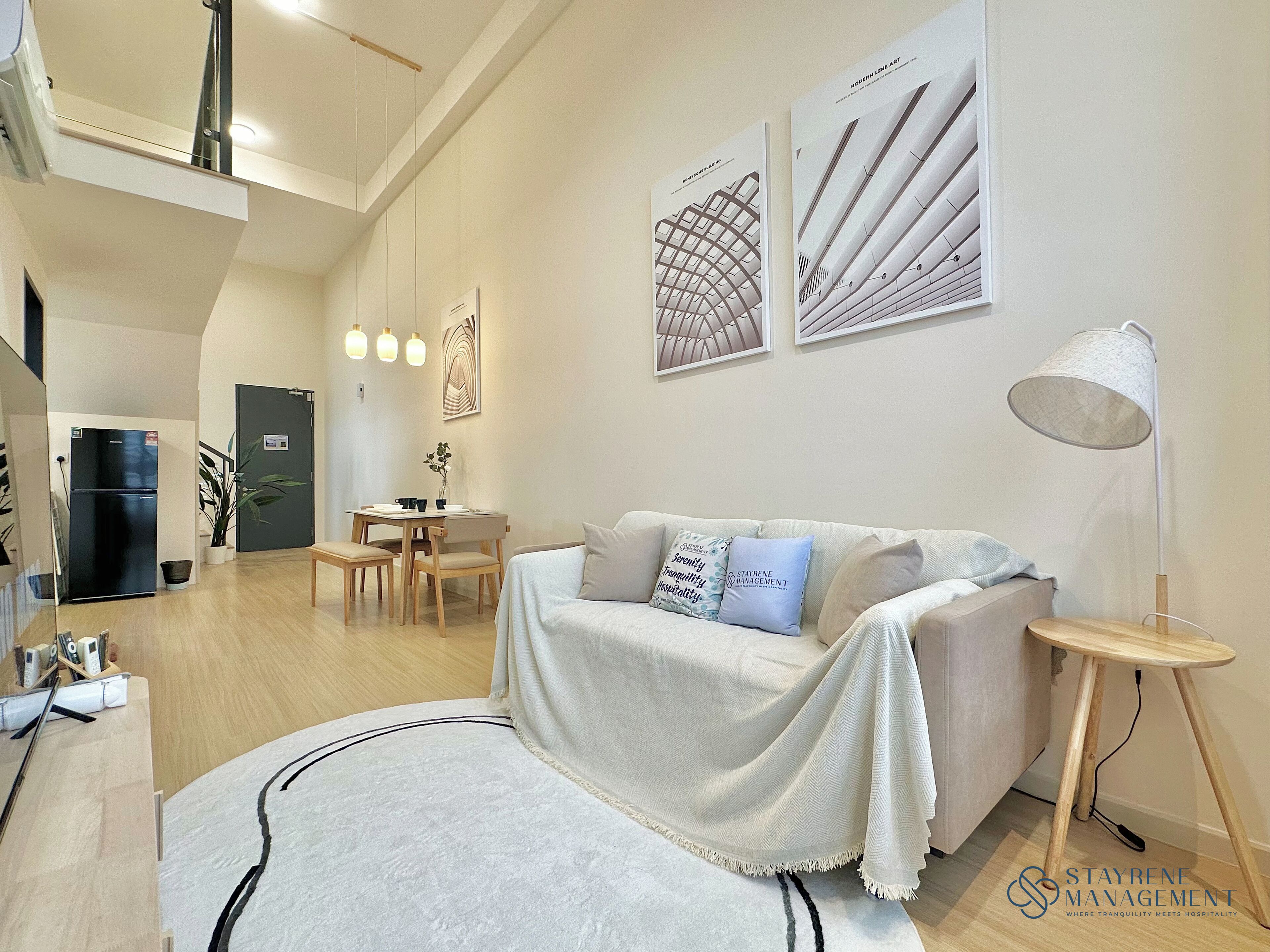 A modern living room with a sofa, a dining table, and a kitchen area.