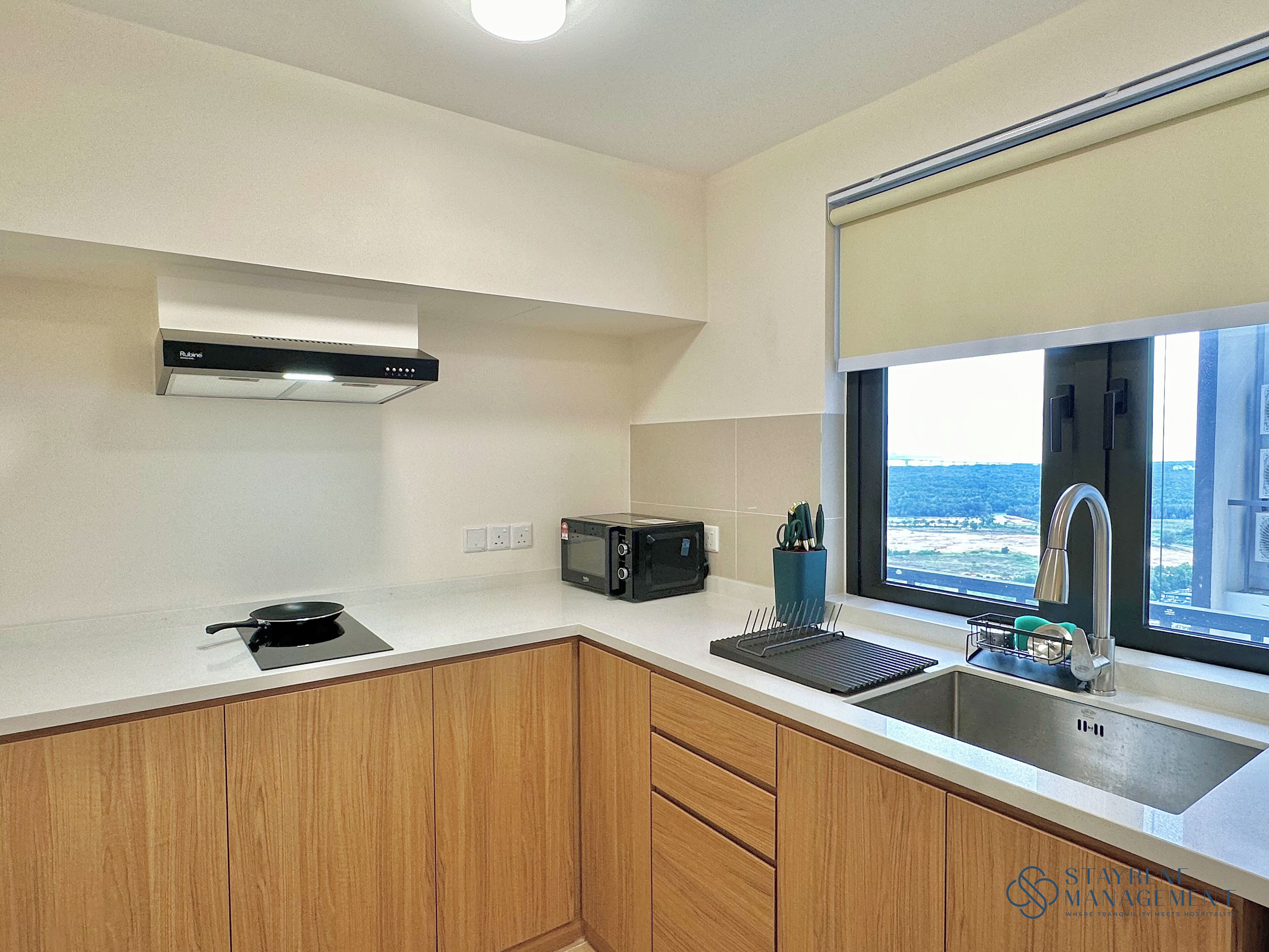 A compact kitchen with a microwave, toaster, and sink. There's a window with a view of the sea.