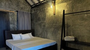 Una camera da letto con un letto, un comodino, una mensola a muro e una finestra con tende.