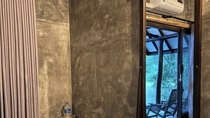 Ein Zimmer mit einem großen Spiegel, der einen Außenbereich, eine Wasserflasche und ein Glas auf einem schwarzen Beistelltisch reflektiert.