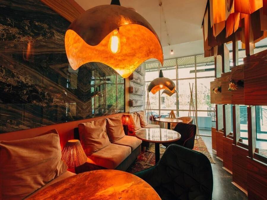 Een modern interieur met een bank, ronde tafels en hanglampen.