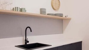 Eine moderne Küche mit einem schwarzen Spülbecken, einer weißen Arbeitsplatte und dunklen Schränken.