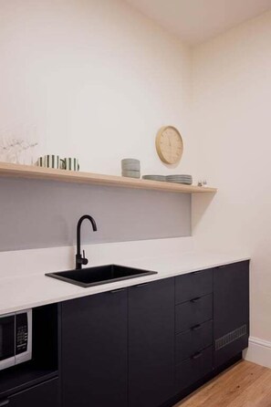 A modern kitchen with a black sink, white countertop, and dark cabinets. - Palfreymans Arcade | Central NoHo 2 Bed Apartment - 1 (Hobart City)