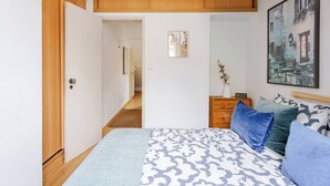 A bedroom with a bed, pillows, a nightstand, a framed picture, and a door leading to another room. - Trendy Loft Heart Of The City! (Lisbon)